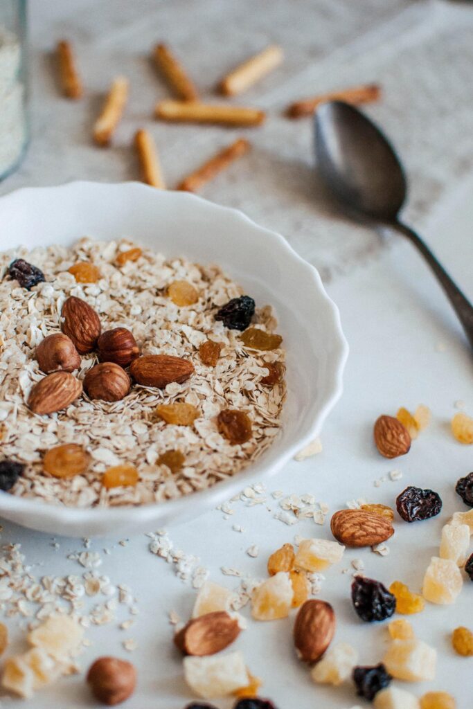 White bowl of porridge with raisins, nuts and dried fruit.